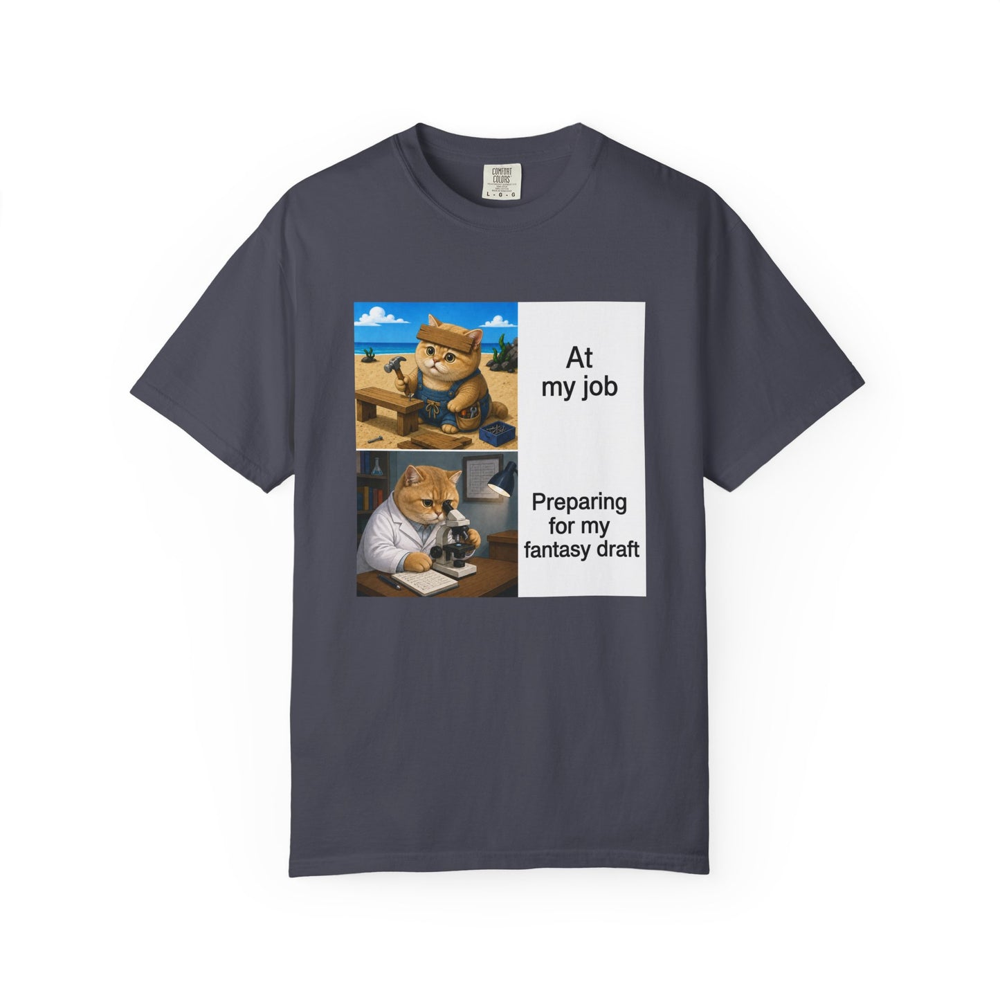 Navy Comfort Colors 1717 t-shirt with a square two-panel print on an off-white card across the chest: an orange cat in denim overalls hammering a nail into a wooden bench on a beach, captioned At my job, above the same cat in a white lab coat hunched over a microscope beside a notebook of stats, captioned Preparing for my fantasy draft.
